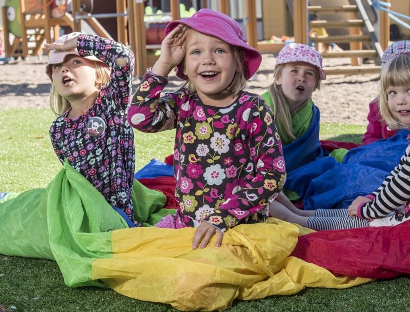 Kids sitting in the yard on colorful fabric and looking over the camera